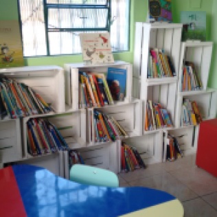 Novo espaço para os livros infantis com estante construida com caixas de frutas.